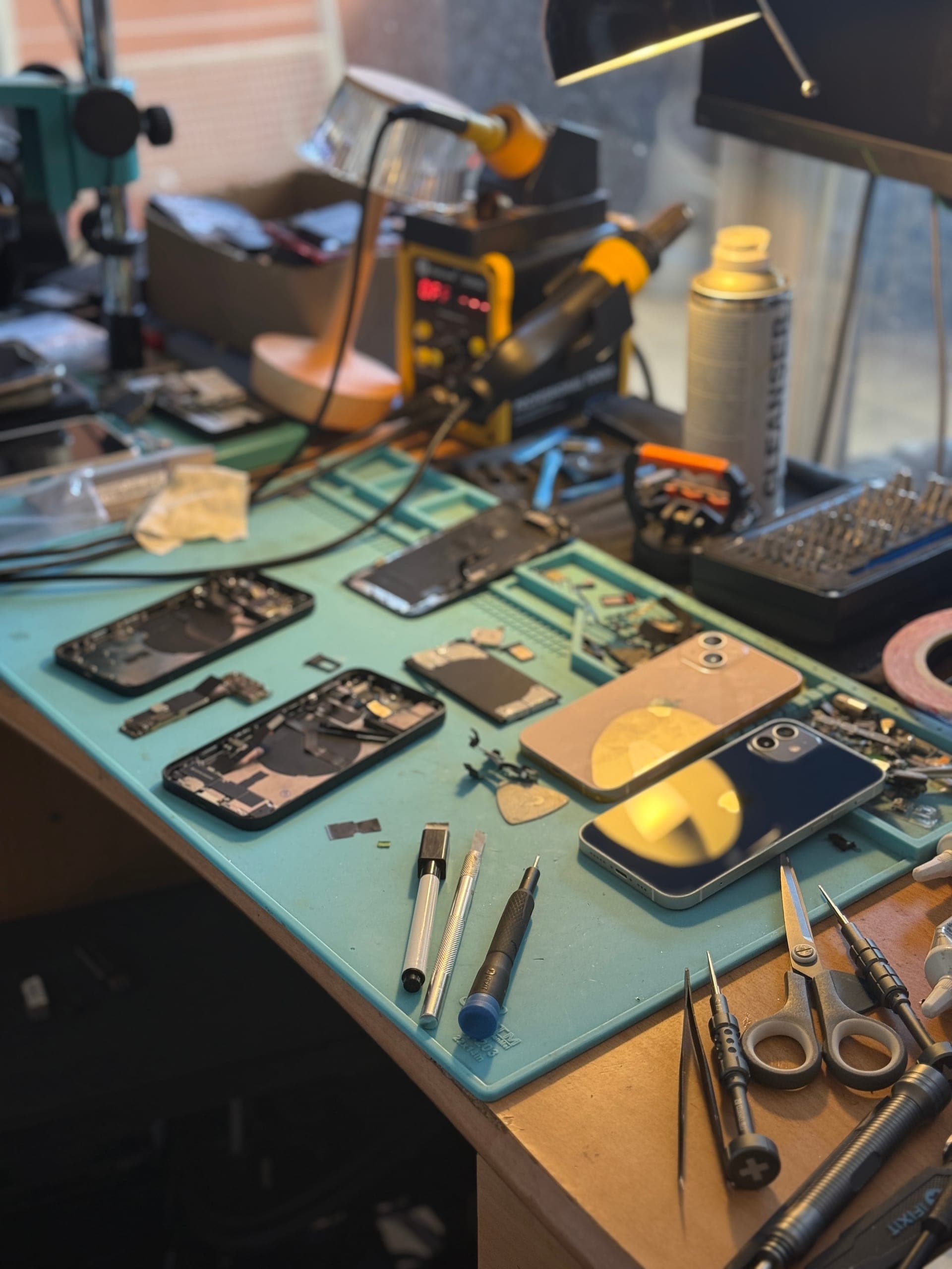 Établi de réparation de l'Atelier de Sam à Poitiers — smartphones démontés, station de soudure et outils de précision, artisan agréé QualiRépar